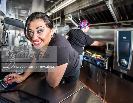 Dark haired smiling cashier with blue eyes on food truck