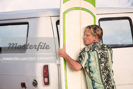 One middle aged man lifting heavy surfboard