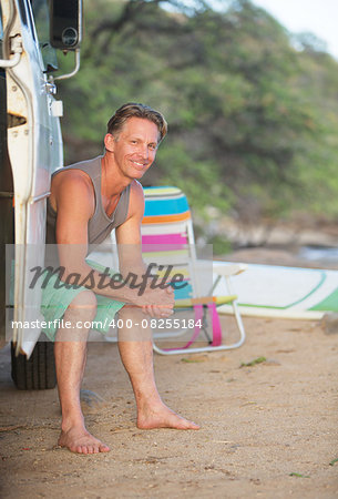 Adult male surfer sitting in van door on beach