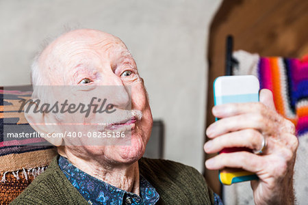 Older man looking at camera while taking silly face selfie