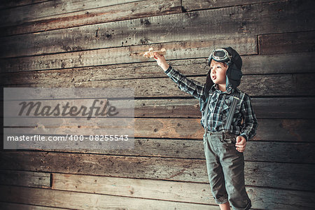 Boy with airplane on the background of wooden wall