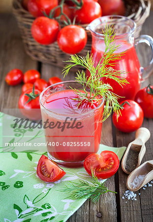 Tomato juice and fresh tomatoes on wooden table