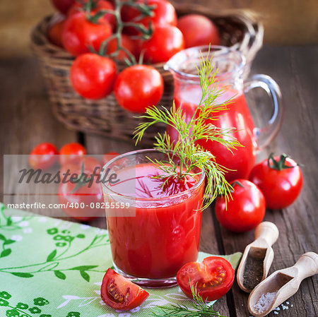 Tomato juice and fresh tomatoes on wooden table