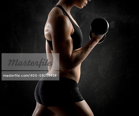 Athletic muscular woman training biceps with dumbbells