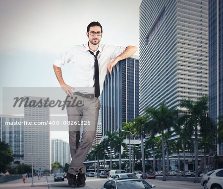 Giant successful businessman leaning against a skyscraper