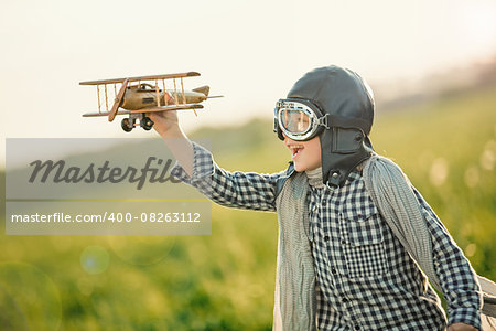 Little boy with wooden airplane in the field