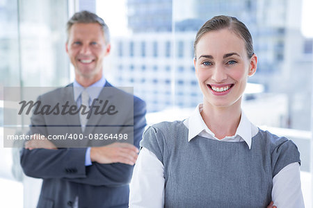 Businesswoman smiling at the camera while her colleague smiling in the background