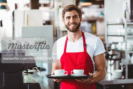 Handsome barista holding two cups of coffee in the cafe