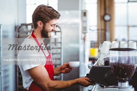 Handsome barista using the coffee machine at the cafe