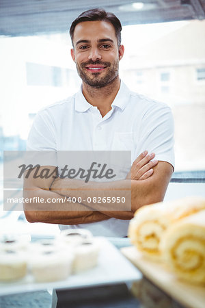 Smiling server in apron arm crossed at the bakery