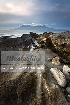 Looking towards Isle of Rum at twilight from rocks at Singing Sands (Camas Sgiotaig), Isle of Eigg, Inner Hebrides, Scotland, United Kingdom, Europe