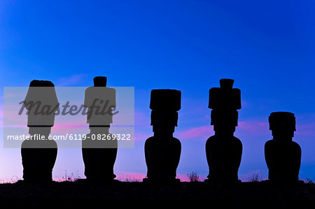 Anakena beach, monolithic giant stone Moai statues of Ahu Nau Nau, four of which have topknots, silhouetted at dusk, Rapa Nui (Easter Island), UNESCO World Heritage Site, Chile, South America