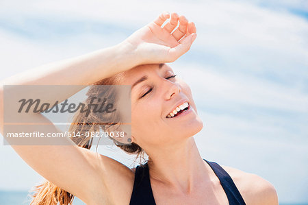 Mid adult woman on beach, arm resting on head