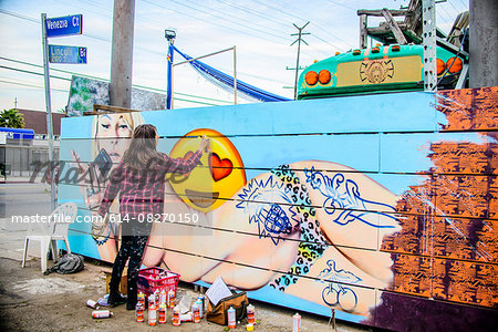 Graffiti artist spray painting wall, Venice Beach, California, USA