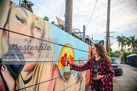 Graffiti artist spray painting wall on street, Venice Beach, California, USA