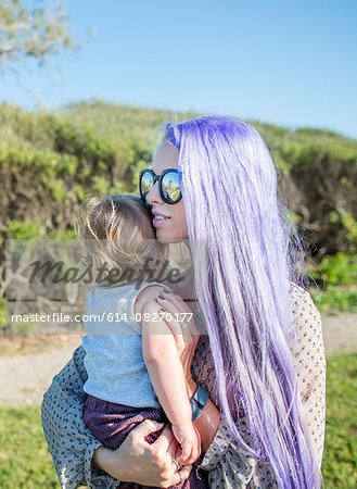 Young woman with long purple hair,  holding baby daughter