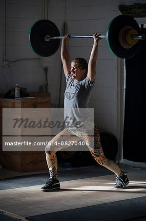 Crossfitter lifting barbell in gym