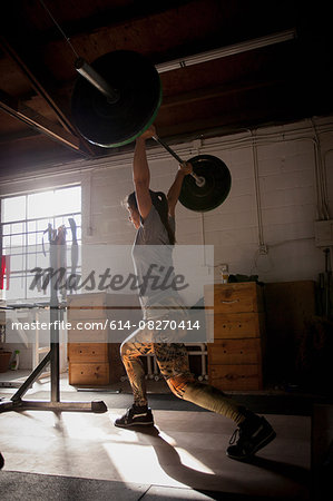 Crossfitter lifting barbell in gym