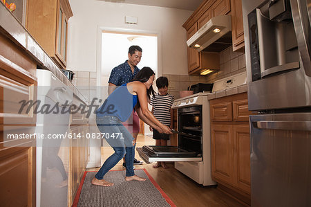 Boy and parents putting tray into kitchen oven