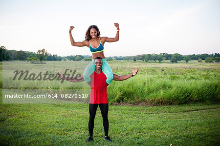 Portrait of young man training with girlfriend on his shoulders