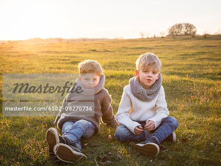 Boys sitting together on meadow