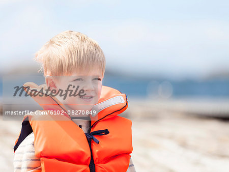 Boy wearing life jacket looking away