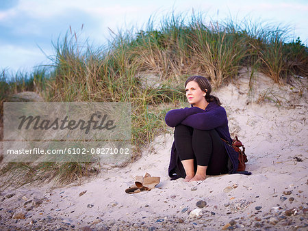 Woman sitting on sand dune