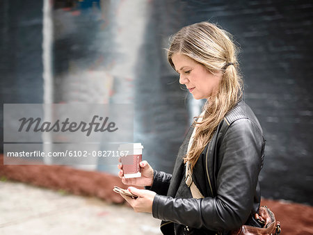 Woman with coffee using cellphone