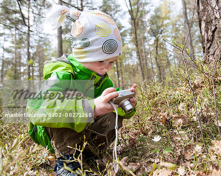 Boy taking picture in forest