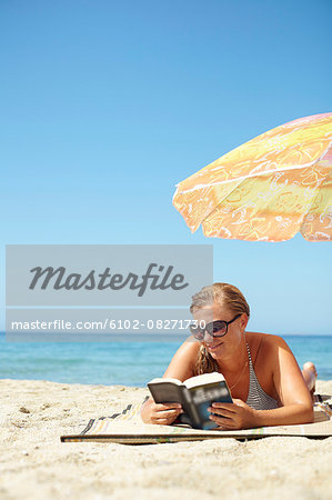 Woman reading book on beach