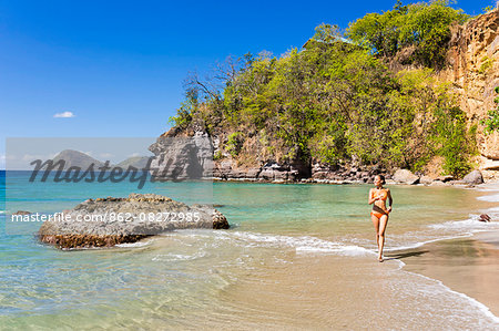 Dominica, St John Parish, Portsmouth, Secret Bay. A young lady runs along Secret Beach..