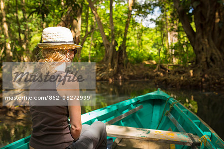 Dominica, Portsmouth. A young woman sits on a boat on the Indian River, one of Dominica's most popular tourist attractions. . Dominica, Portsmouth. A young woman sits on a boat on the Indian River, one of Dominica's most popular tourist attractions. .