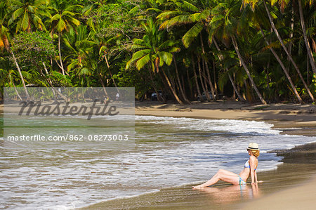 Dominica, Calibishie. A young woman sits in the sea at Batibou Beach. . Dominica, Calibishie. A young woman sits in the sea at Batibou Beach. .