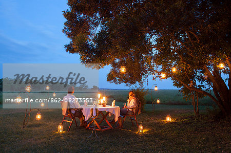 Kenya, Mara North Conservancy. A couple enjoy a romantic dinner overlooking the Mara.