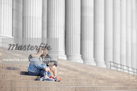 Couple sitting on steps, columns on background