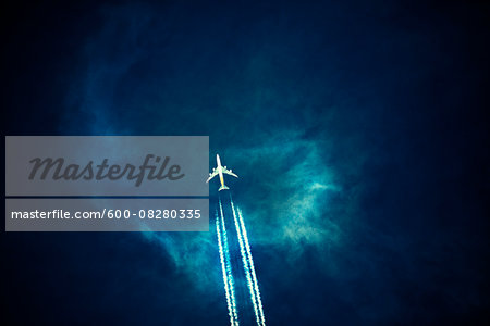 Commercial Airplane with Contrails in Dark Sky