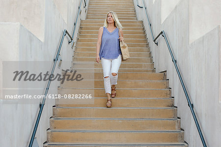Blond woman walking down a staircase.