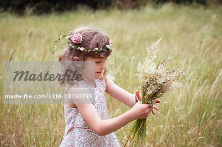 Young girl with flowers in her hair picking wild flowers in a meadow.