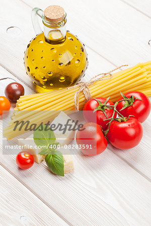 Italian food cooking ingredients. Pasta, tomatoes, basil on wooden table