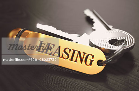 Keys and Golden Keyring with the Word Leasing over Black Wooden Table with Blur Effect. Toned Image.