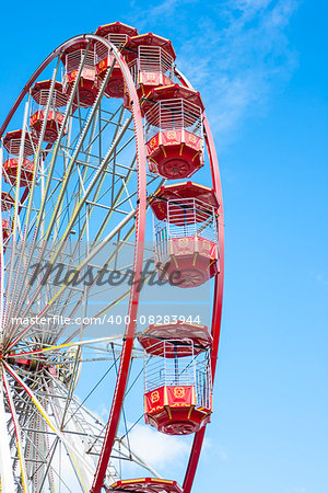 Red Ferris Wheel against blue sky at amusement park