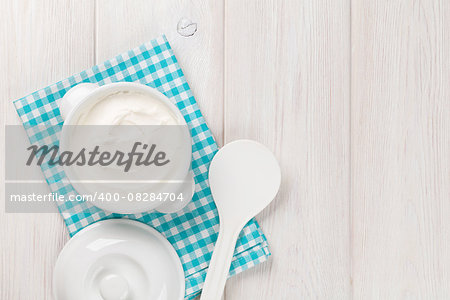 Sour cream in a bowl on wooden table. Top view with copy space