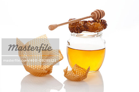 Organic honey with honey comb and wooden dipper isolated on white. Natural healthy sweetener. Alternative medicine.