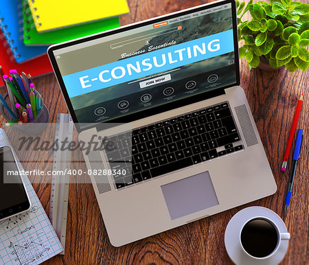 E-Consulting Concept. Modern Laptop and Different Office Supply on Wooden Desktop background.