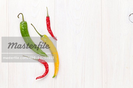 Colorful chili peppers on white wooden table. Top view with copy space