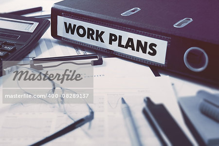 Work Plans - Office Folder on Background of Working Table with Stationery, Glasses, Reports. Business Concept on Blurred Background. Toned Image.