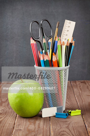 School and office supplies on classroom table in front of blackboard