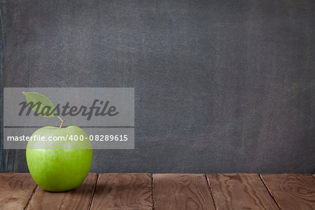 Apple fruit on classroom table in front of blackboard. View with copy space