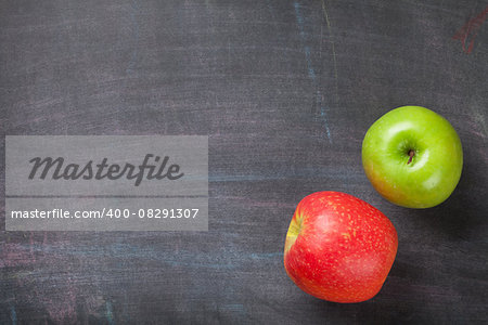 Green and red apples on blackboard or chalkboard background. Top view with copy space