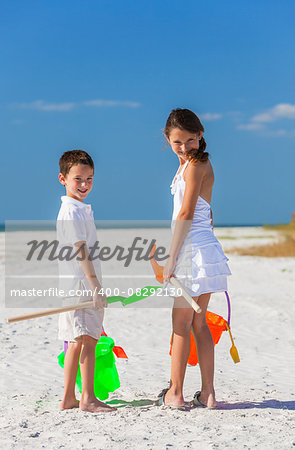 Happy children, boy girl, brother and sister having fun playing in the sand on a beach with bucket and spade